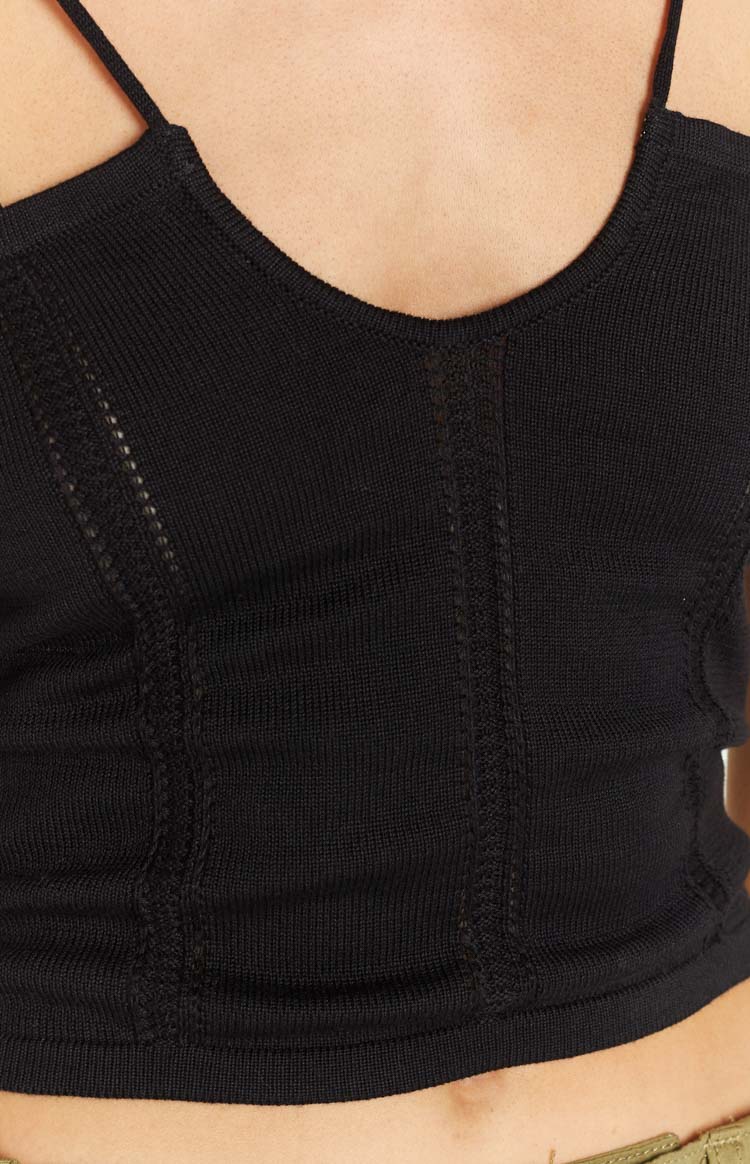 Close-up of the black knit crop top showing the V-neckline and vertical open-knit panel details