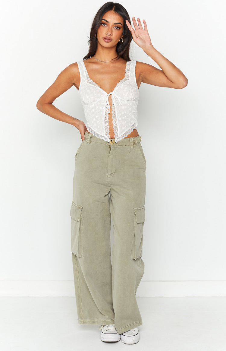 Front view of a white broderie anglaise tie-front crop top with scalloped lace trim and pointed hem