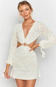 White crochet mini dress with a deep V-neck, long sleeves, and side waist cutouts with a ring