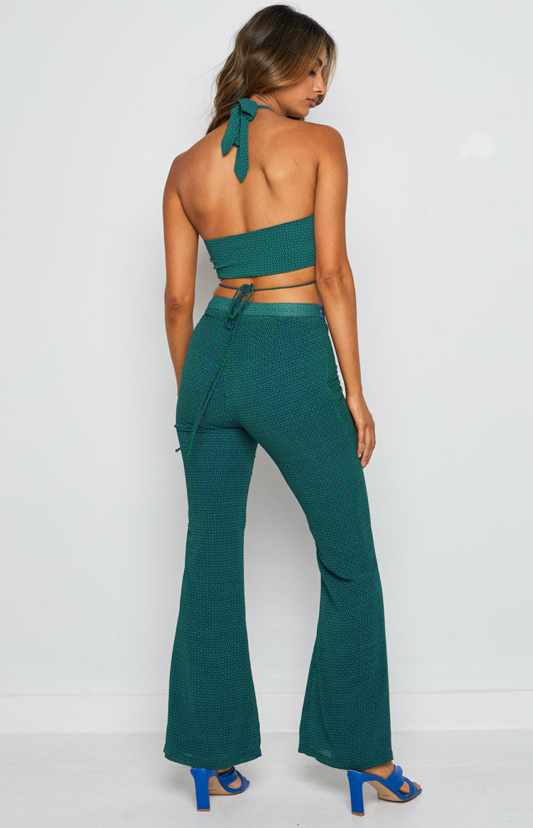 Rear view of teal pants with a small geometric pattern, fitted through the thigh and flared at the hem