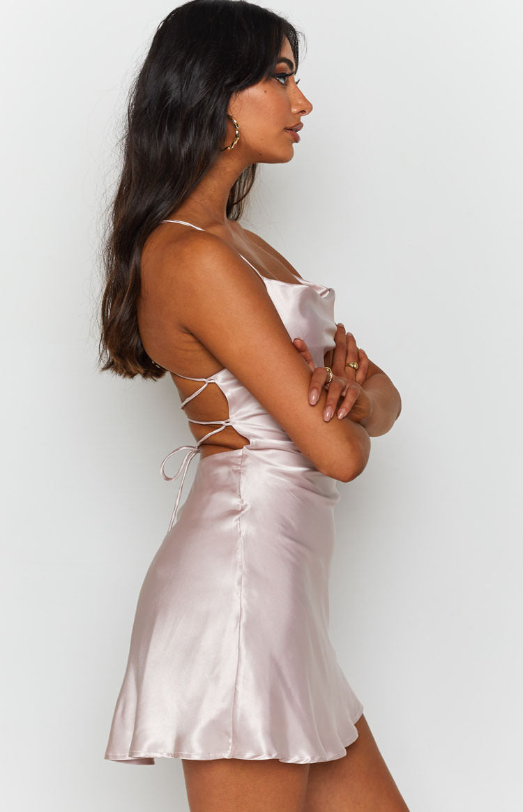 Blush silky mini dress with a draped cowl neck and intricate lace-up side cutouts