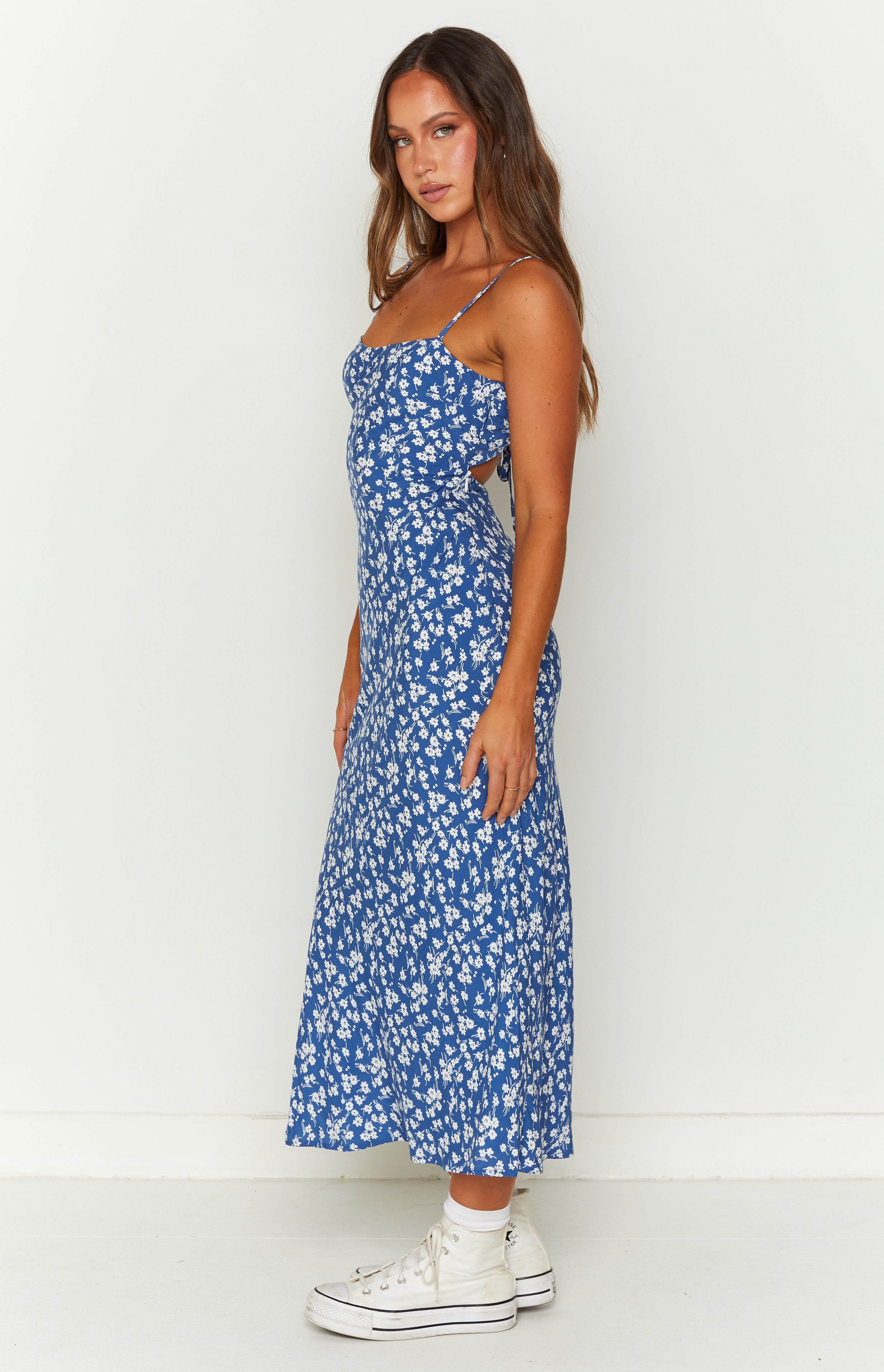 Side view of a blue floral midi dress with a square neckline, spaghetti straps, and side cut-outs with tie details