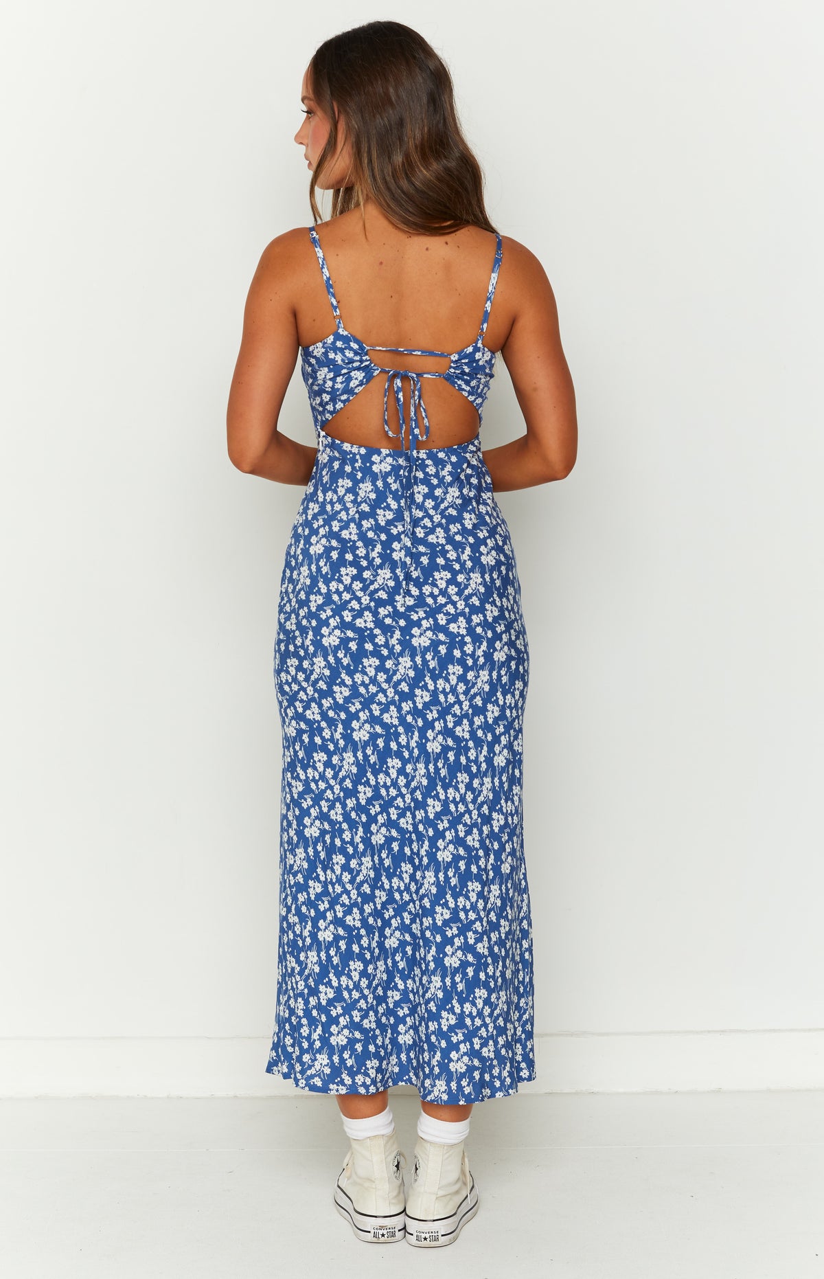 Rear view of a blue floral midi dress with an open back and tie detail