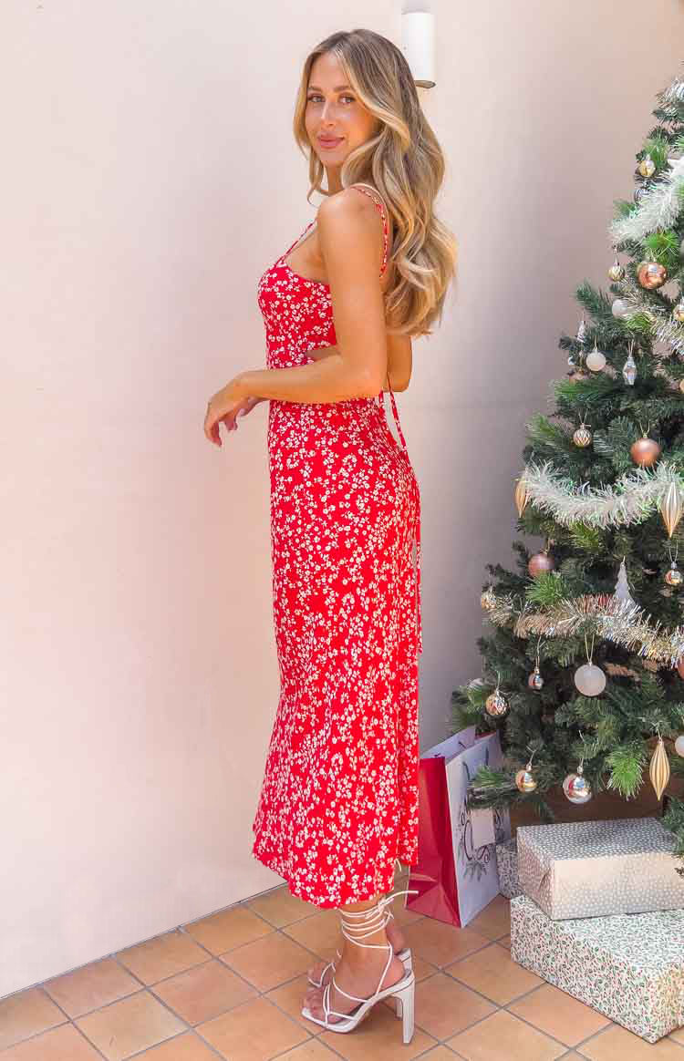 Side view of a red floral midi dress with spaghetti straps and a cutout waist detail