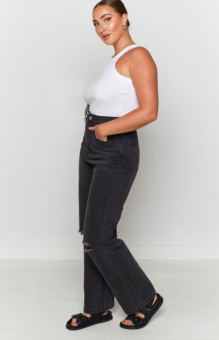 Faded black wide leg jeans featuring distressed knee rips and a raw hem