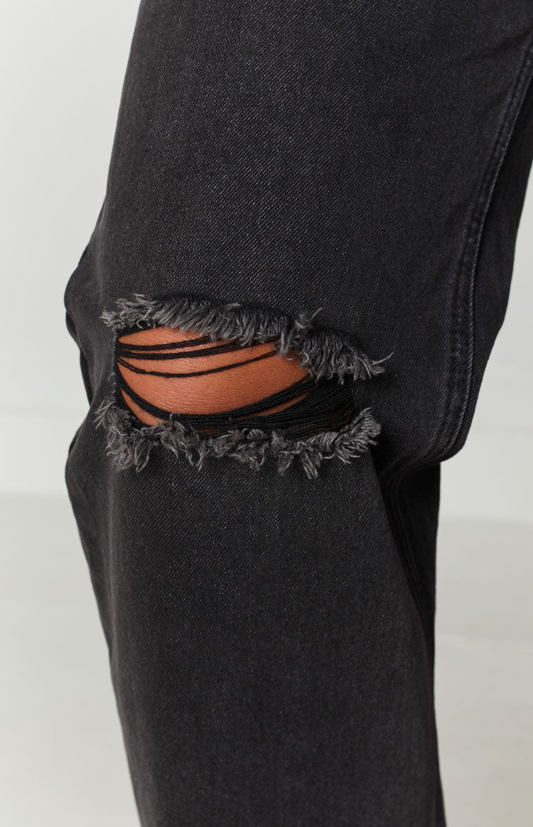 Black wash jeans with a horizontal rip detail and frayed edges on the knee