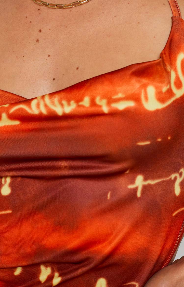 Close-up of the red and orange abstract pattern with yellow script details on the cowl neckline