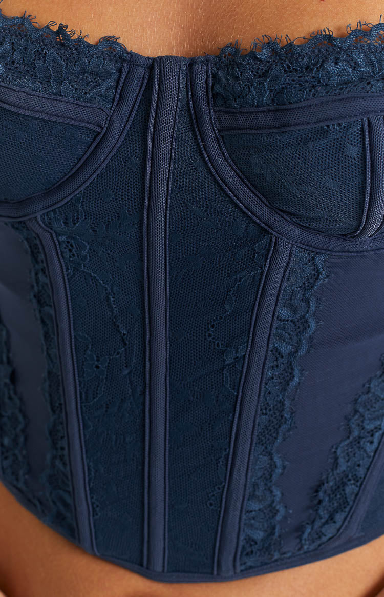 Close-up of the navy blue lace corset top showing the structured boning, sheer mesh, and delicate floral lace pattern