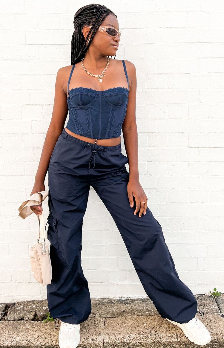 Full front view of a dark blue lace corset top with a structured bodice, thin straps, and cropped hem