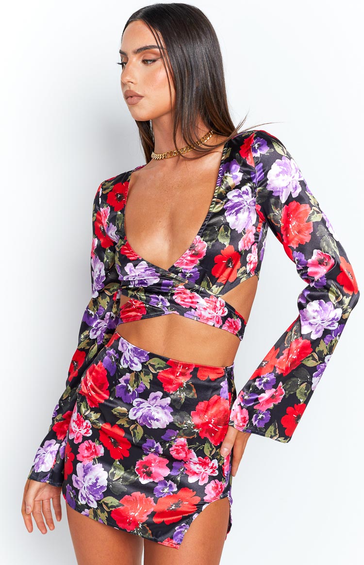 Detail shot of the black satin long sleeve wrap top with red, purple, and pink floral print, showing the deep V-neck and criss-cross waist cutouts
