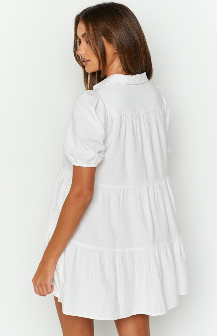 Rear view of a white linen tiered dress with puffed short sleeves and gathered tiers