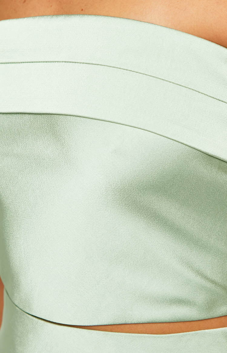 Close-up of the sage green top's textured fabric, layered band detail, and small waist cutout