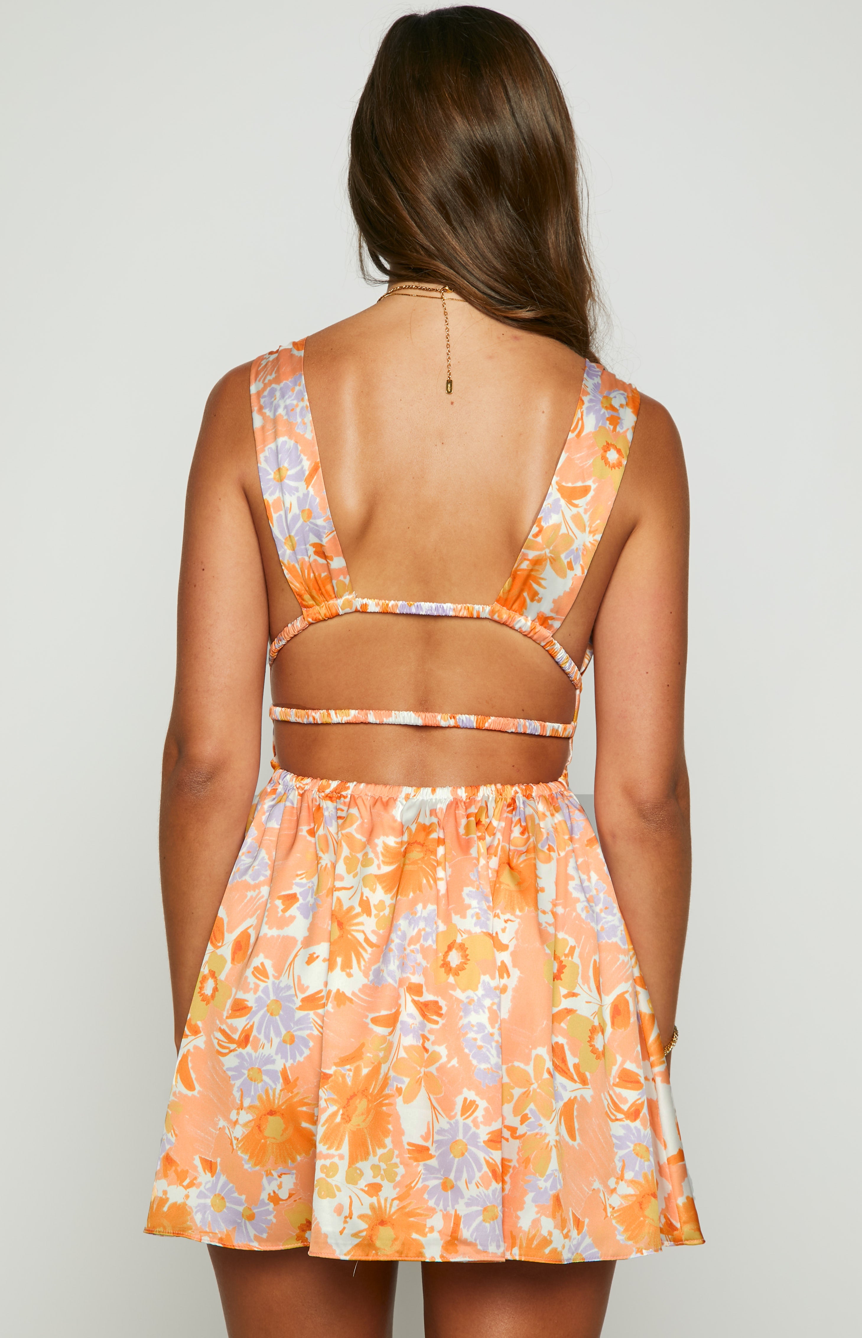Rear view of an orange floral mini dress showing wide cross-back straps, elasticated back band, and cutouts