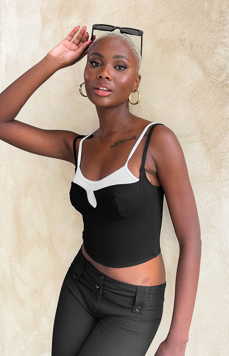 Close-up of the black double layered crop top with white ribbed sweetheart neckline and thin straps