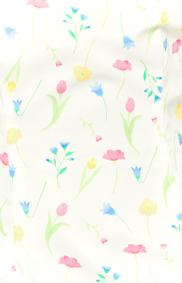 White mini skirt fabric with a delicate scattered floral pattern in pink, yellow, and blue