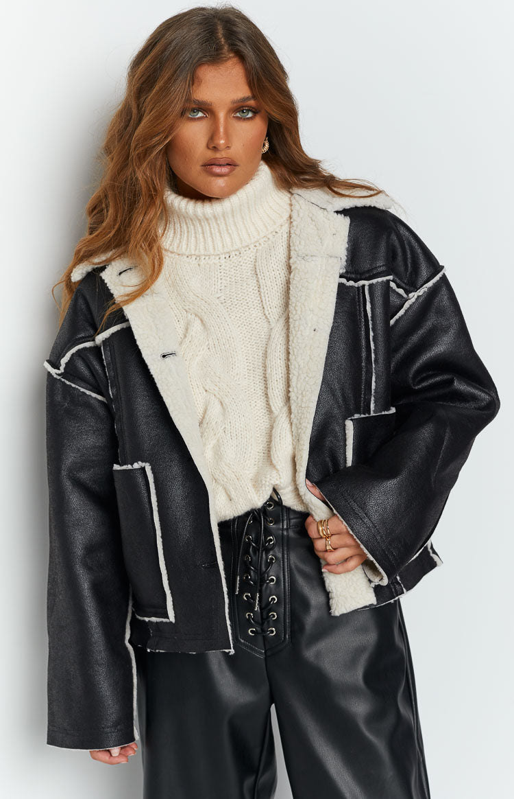Black faux leather jacket with cream faux fur lining and exposed seams, worn open