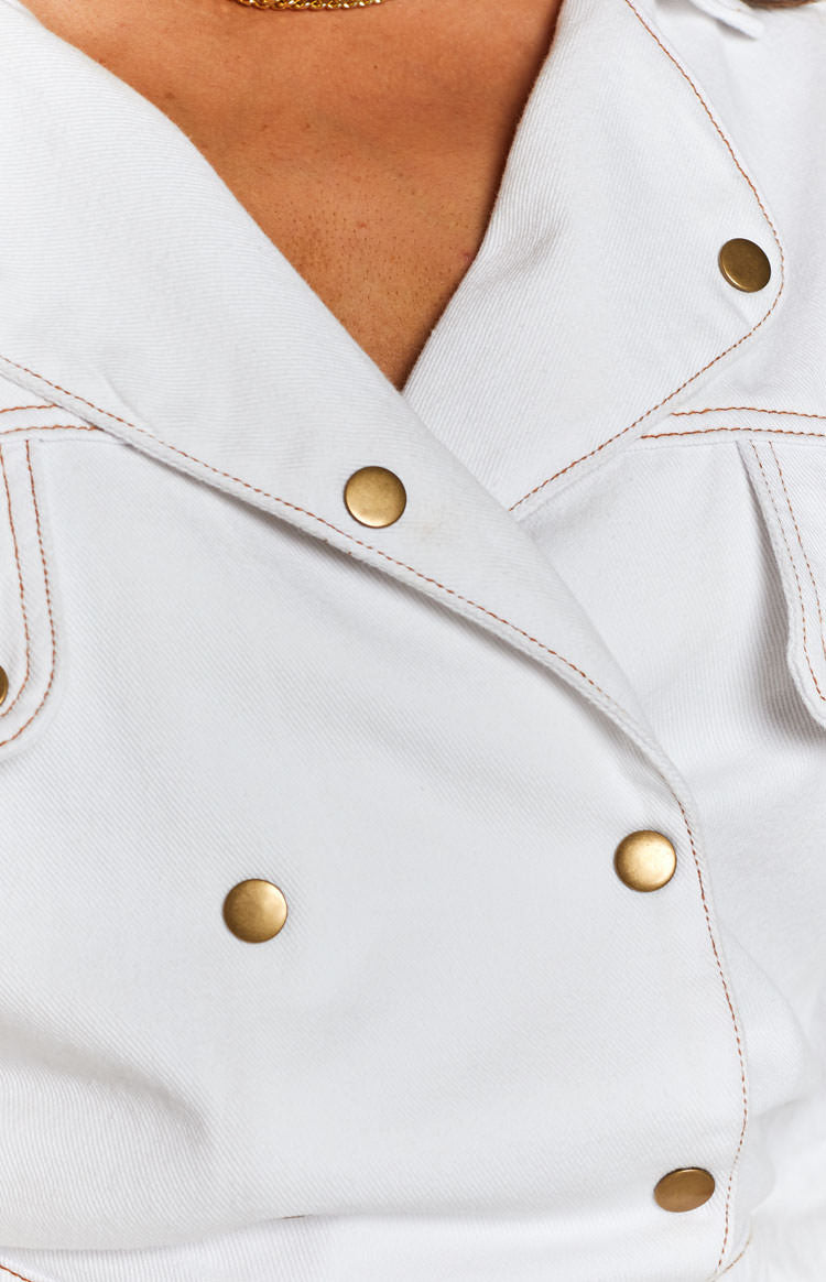 Cream denim jumpsuit with a collared neckline, double-breasted gold snap buttons, and brown topstitching