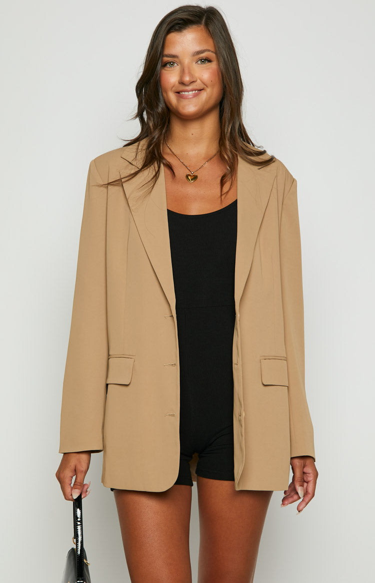 Front view of an open tan oversized blazer with notched lapels and flap pockets