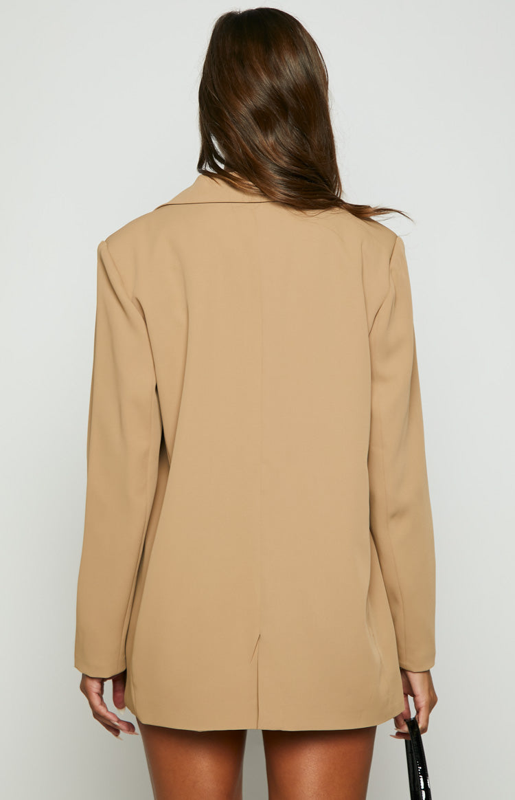 Rear view of a tan oversized blazer with long sleeves and a single vent at the back hem