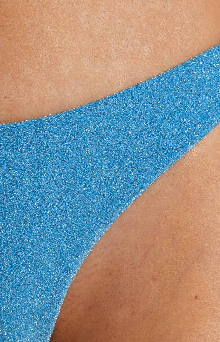 Close-up of the blue glitter fabric of the bikini bottoms, showing the sparkly texture