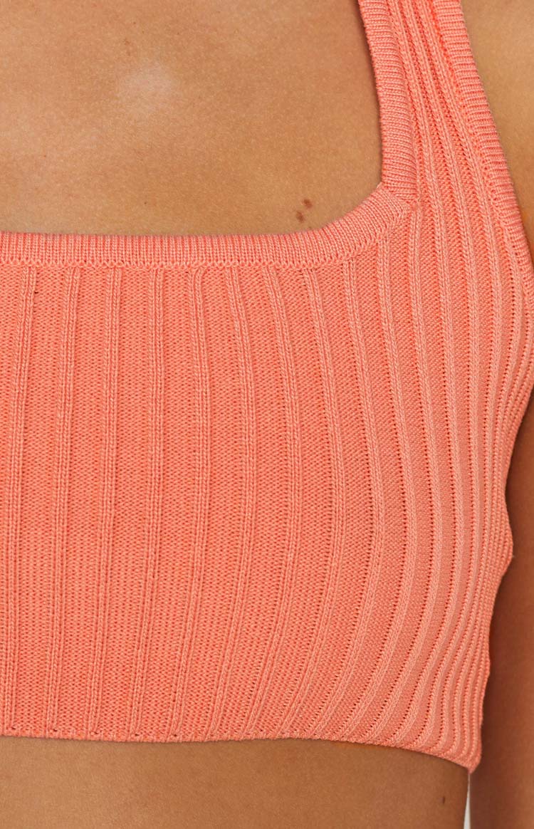 Close-up of the orange ribbed knit fabric and square neckline of the crop top