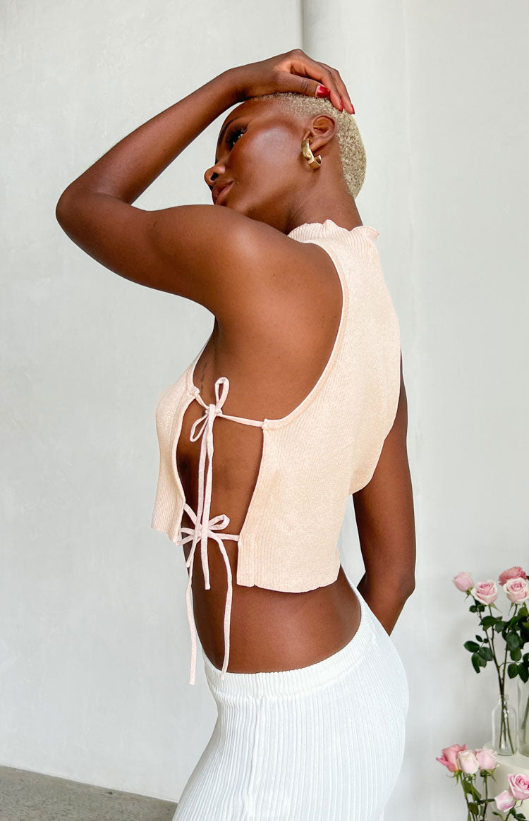 Side view of a light pink ribbed knit crop top with open sides and criss-cross self-tie straps
