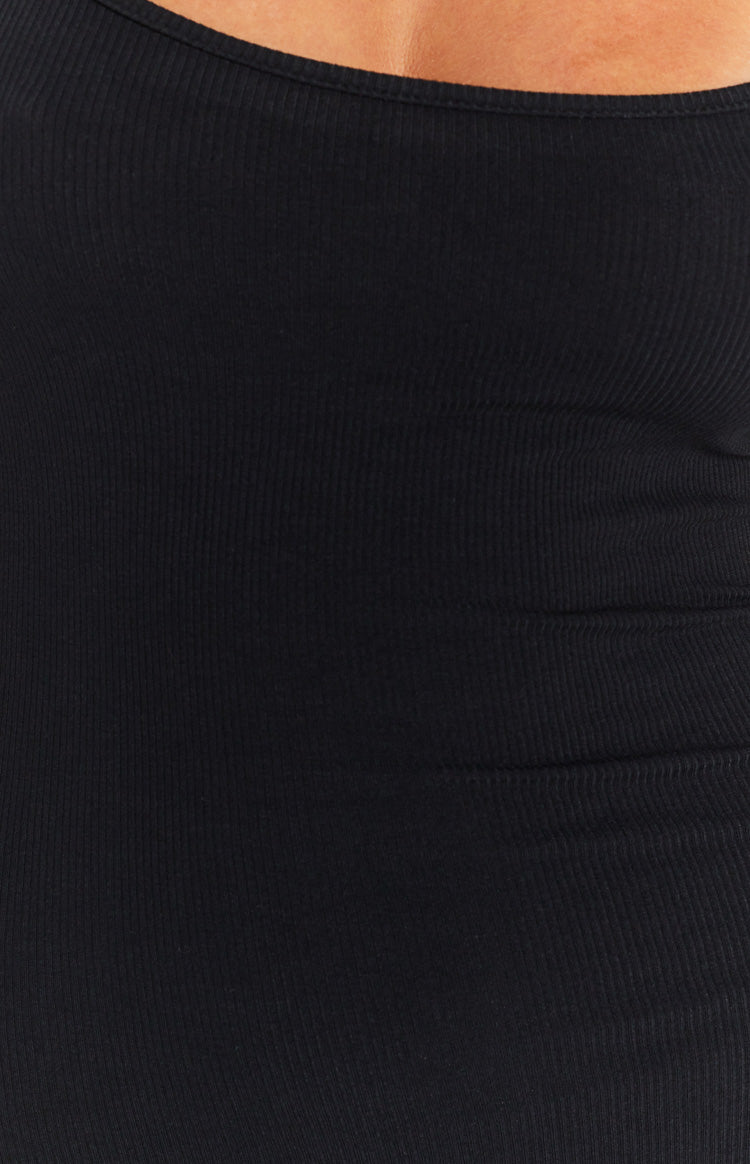 Close-up of the black ribbed knit fabric of the maxi dress, showing the simple finished neckline