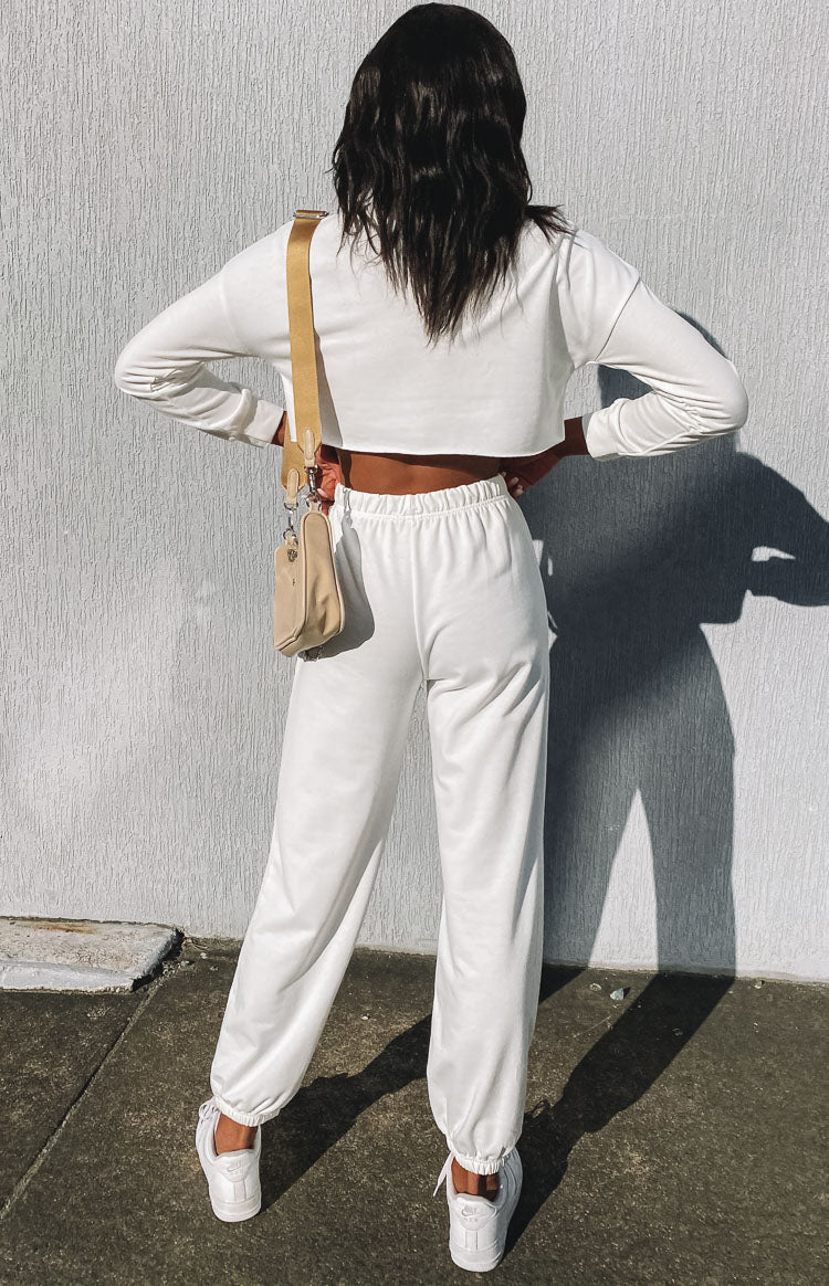 White cropped long sleeve top with raw hem and matching high-waisted jogger pants with elasticated cuffs