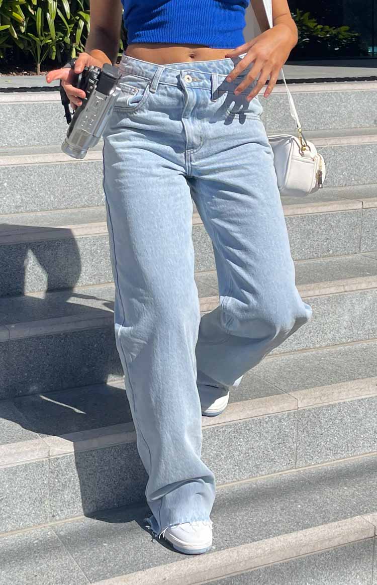 Light blue uneven waist denim jeans with raw hem.