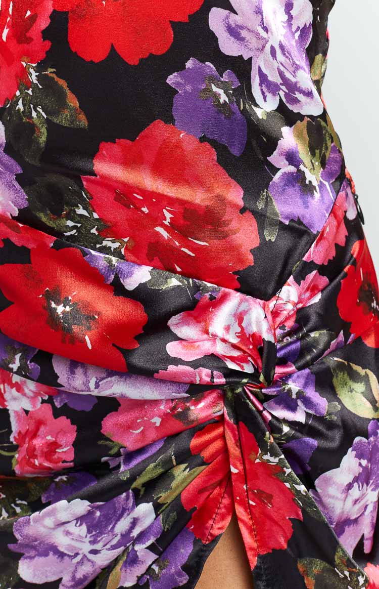 Detail shot of the ruched knot on the side of the black floral mini dress with red and purple flowers