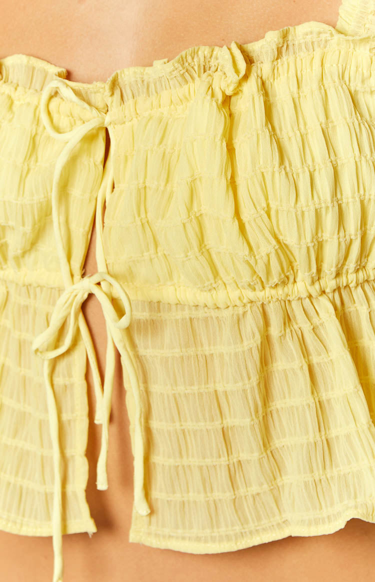Close-up of the yellow smocked crop top showing the tie-front detail and ruffled neckline