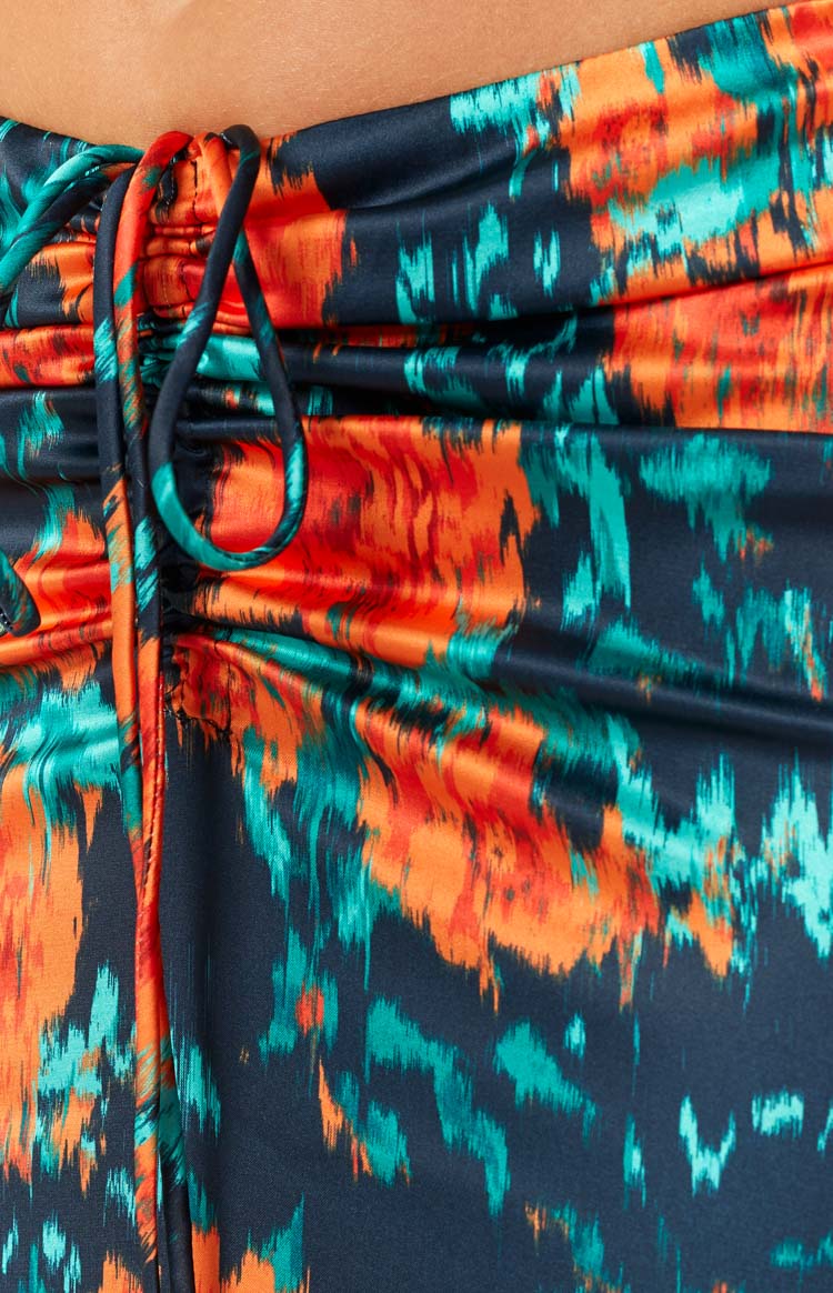 Close-up of the ruched drawstring detail on a dark blue, orange, and teal abstract print satin maxi skirt