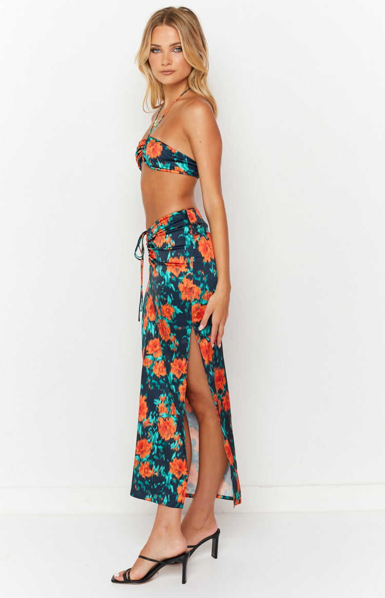 Side view of a dark floral maxi skirt with orange and teal flowers, featuring a high side slit and ruched drawstring detail