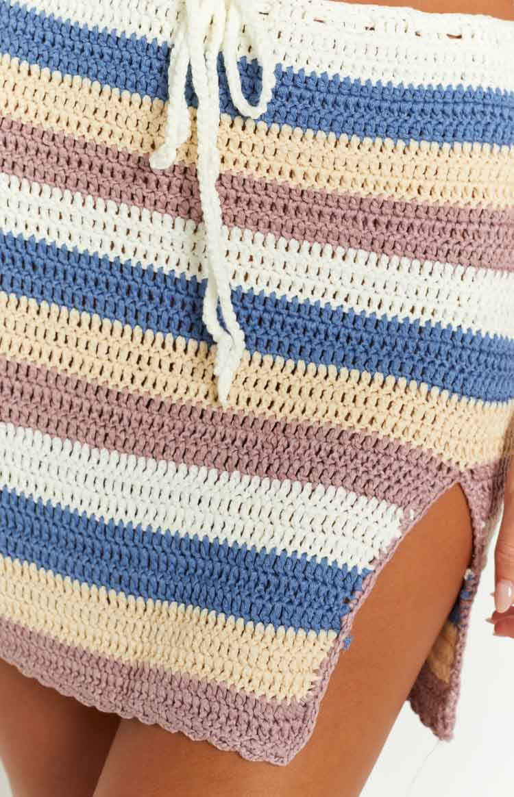 Close-up of the striped crochet mini skirt in white, blue, beige, and purple, featuring a white drawstring and side split