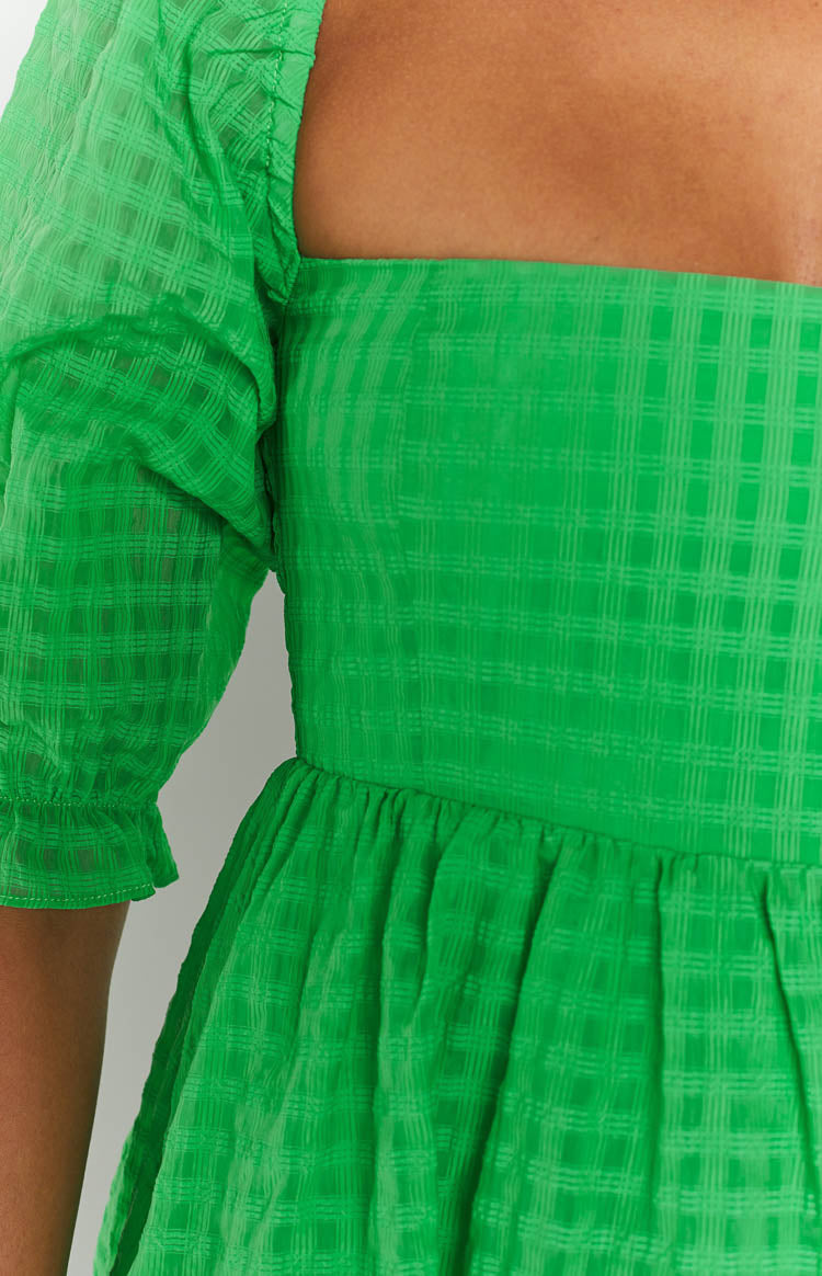 Close-up of the green babydoll dress with a square neckline, puffed sleeves, and gathered waist in a check texture