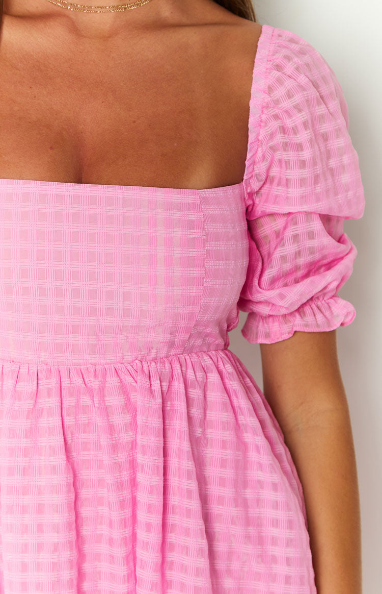 Close-up of the pink babydoll mini dress showing the subtle check texture, puffed sleeves, and ruffled cuffs