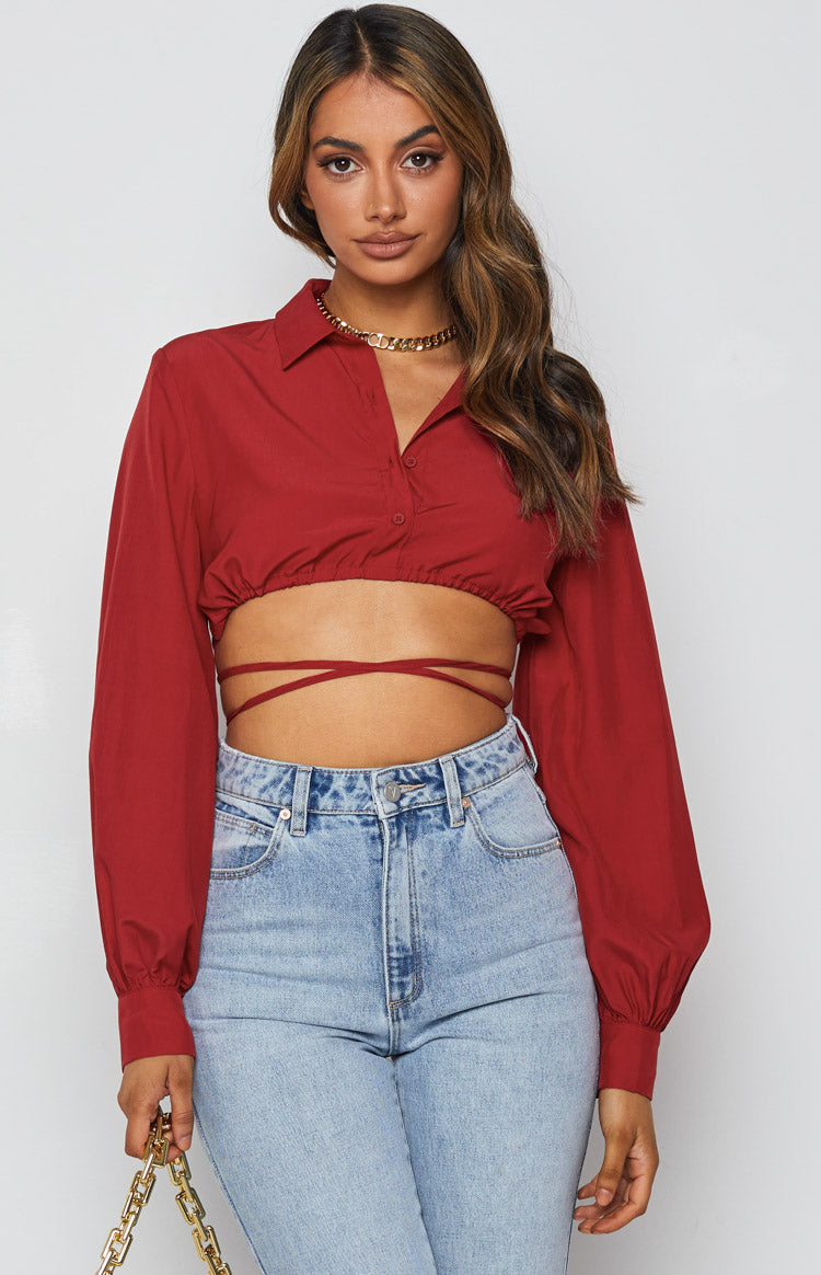 Front view of a red collared crop top with long sleeves, elasticated hem, and wrap-around waist ties