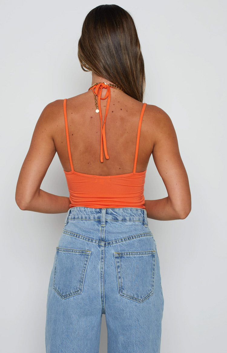 Rear view of an orange ribbed knit crop top with a halter neck tie and thin spaghetti straps