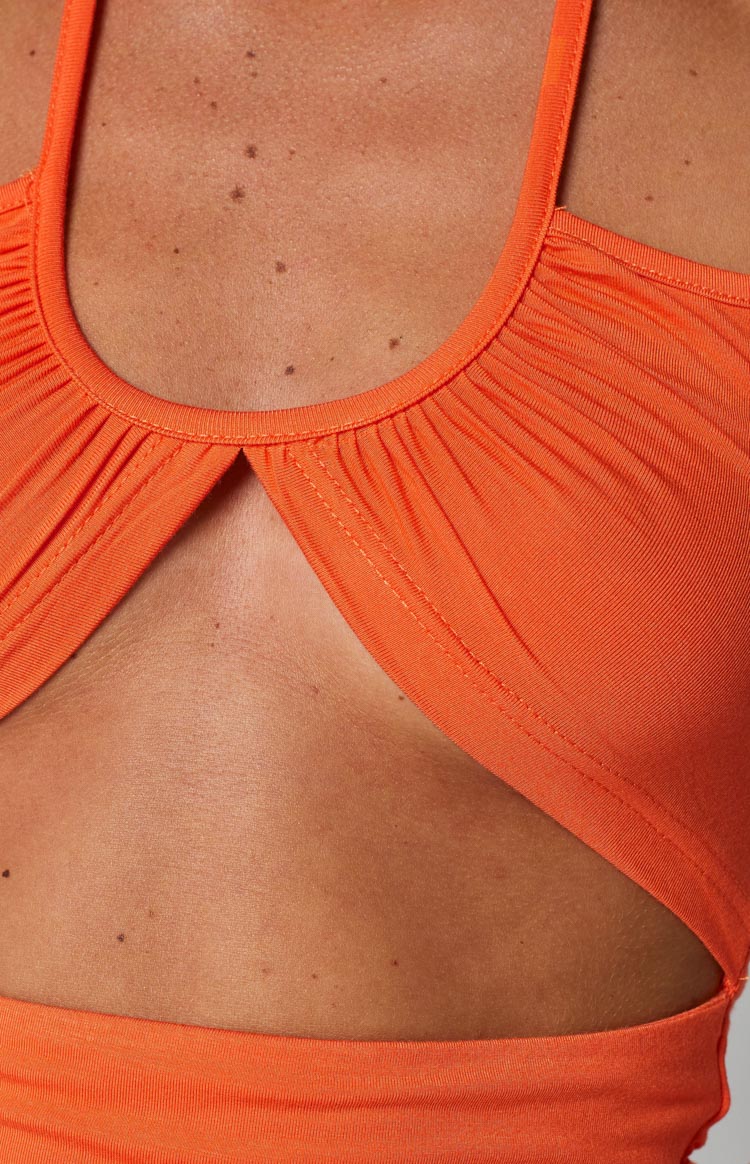 Close-up of the orange ribbed crop top's ruched scoop neckline and triangular front cutout