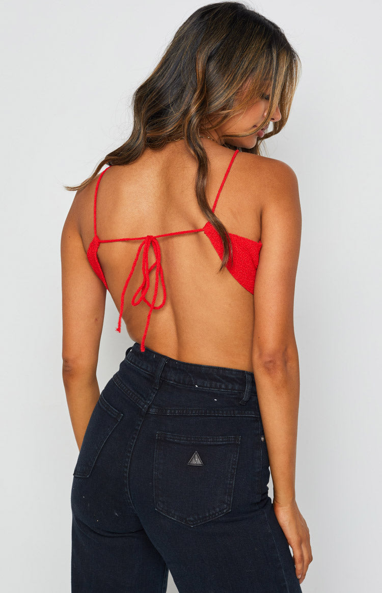 Back view of the red textured halter crop top featuring thin spaghetti straps and an adjustable tie-back closure