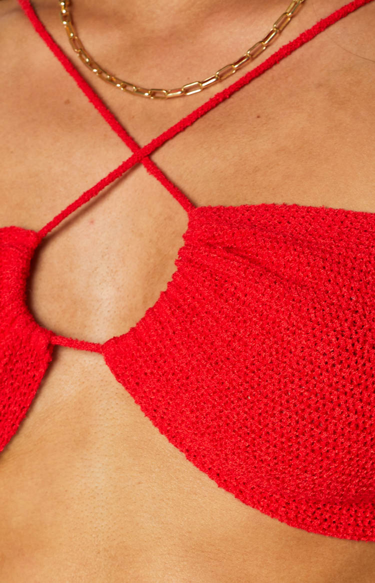 Close-up of the red open knit fabric and thin criss-cross halter straps of the crop top