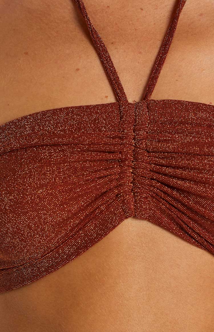 Close-up of the central ruched detail on a rust shimmery knit halter top with thin straps