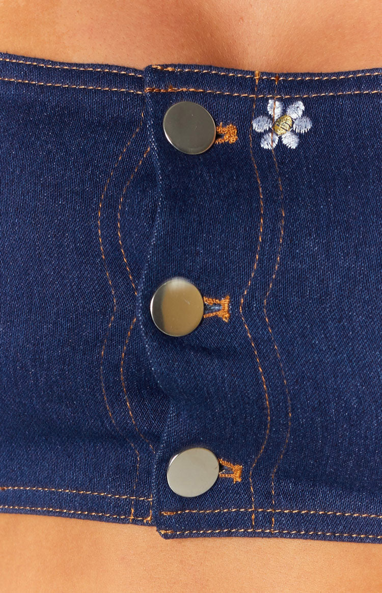 Indigo denim crop top with silver button placket, orange contrast stitching, and white daisy embroidery