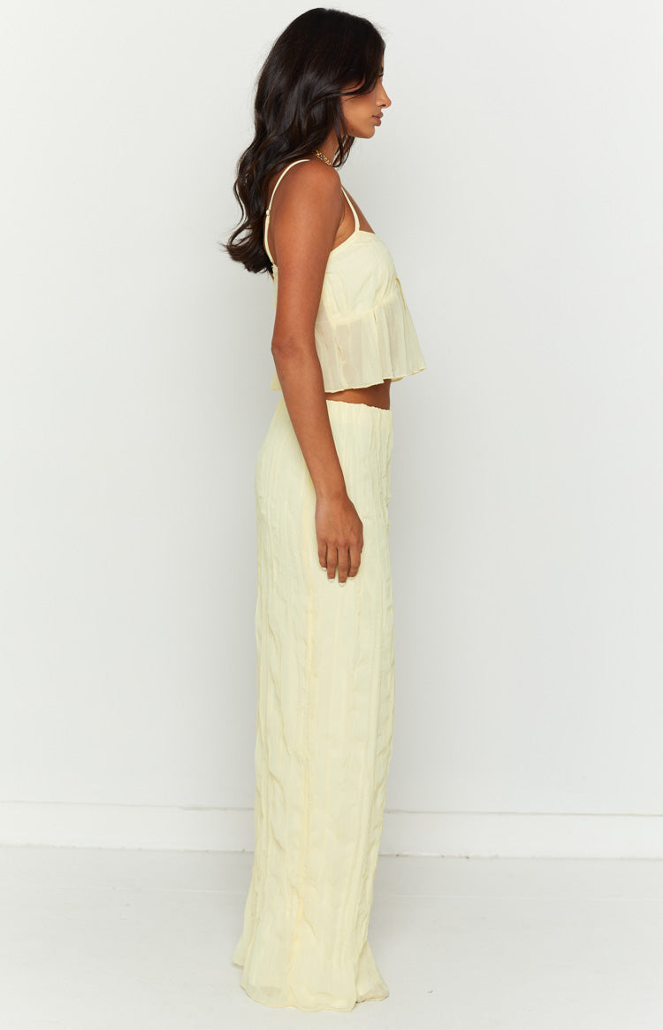Side view of a yellow crinkled maxi skirt with a flowy silhouette and sheer overlay