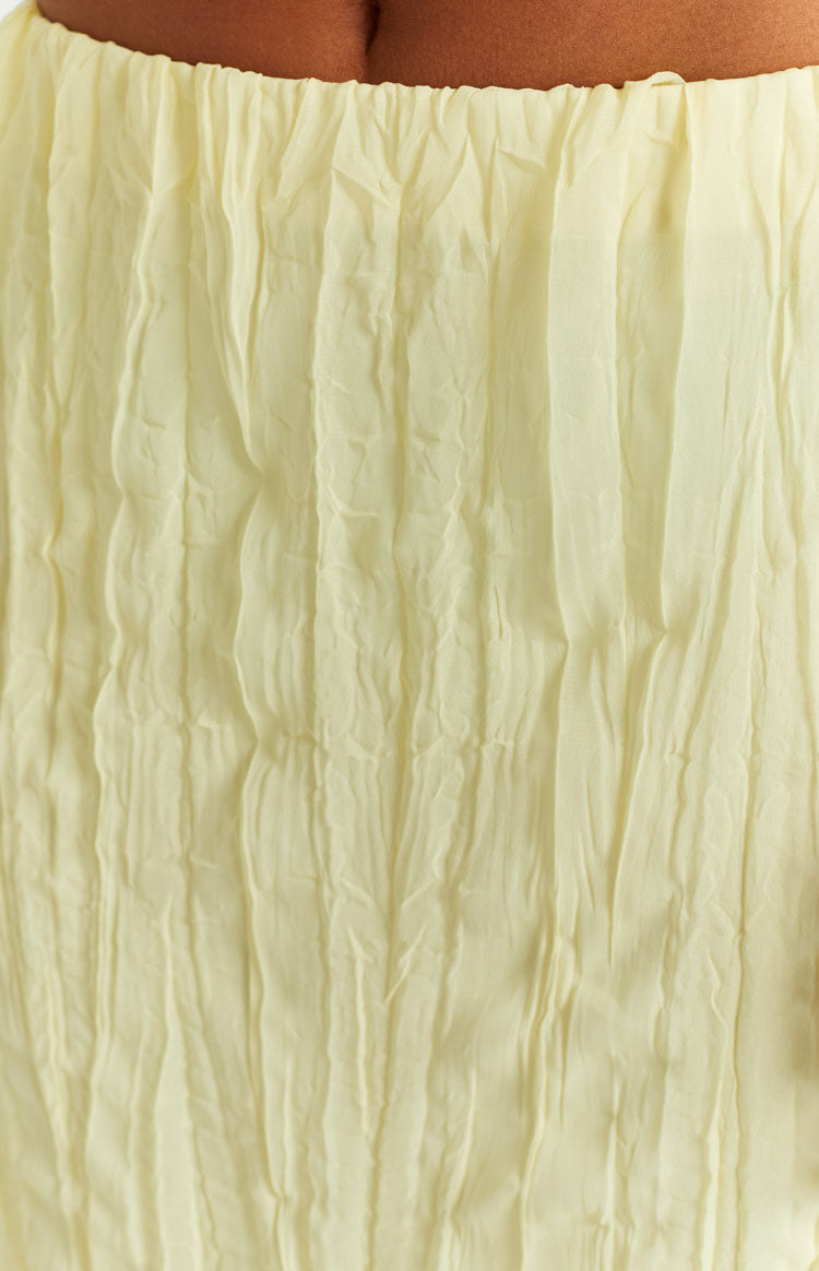 Close-up of the crinkled yellow fabric of the maxi skirt with a gathered elasticated waistband
