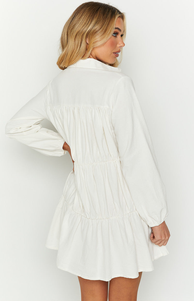 White collared tiered dress with long cuffed sleeves and shirred back and waist details
