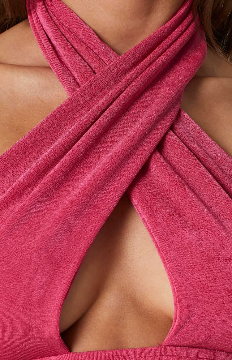 Close-up of the pink cross-neck detail showing the textured knit fabric and deep V-neckline of the top