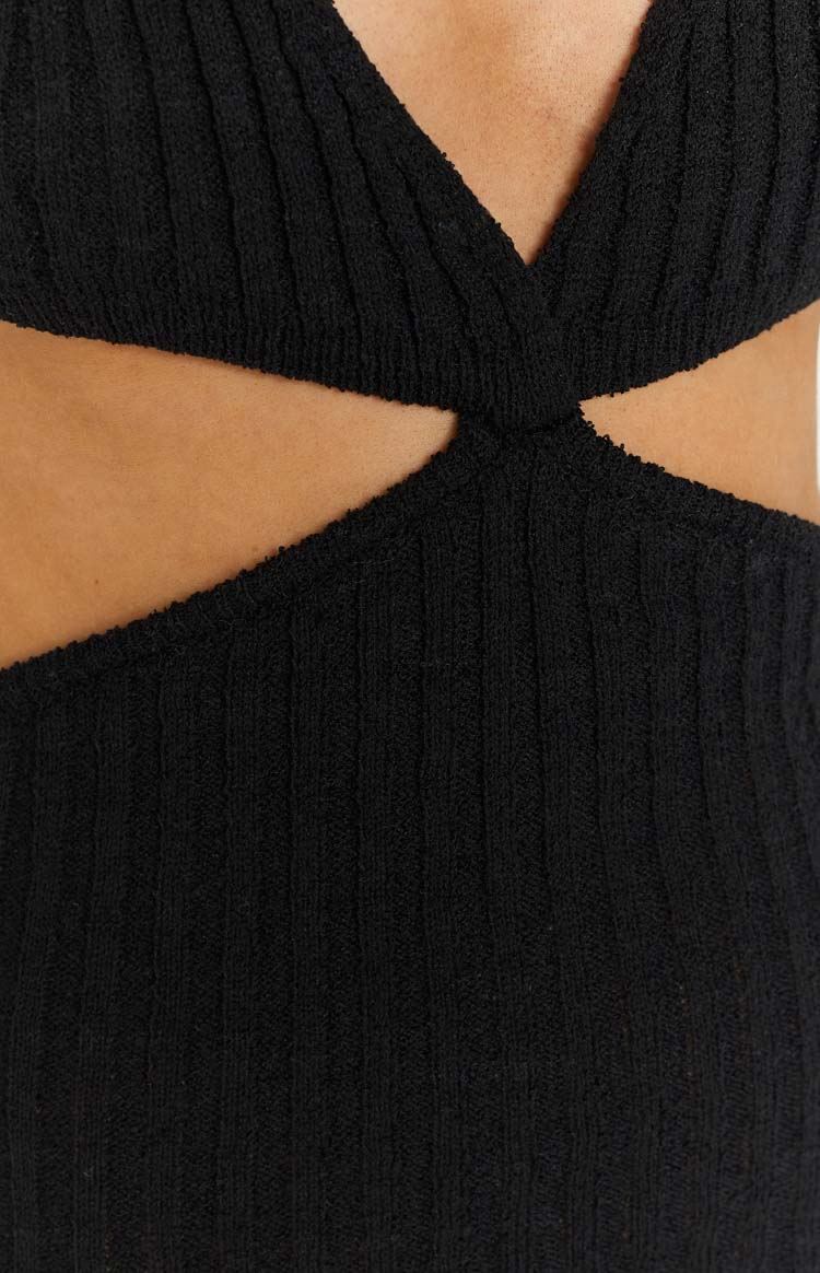 Close-up of the twisted fabric detail creating the side cut-out on a black ribbed knit mini dress