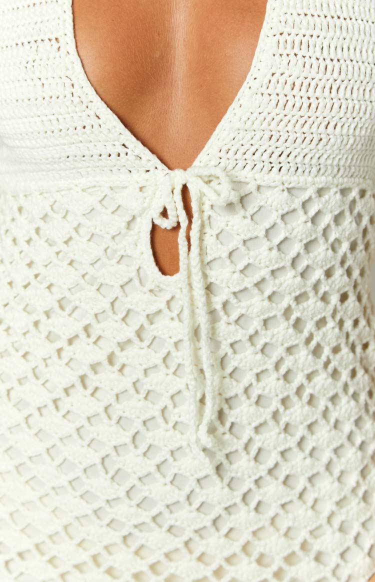Close-up of the cream crochet mini dress with a V-neckline, central tie-front, and open net-like pattern