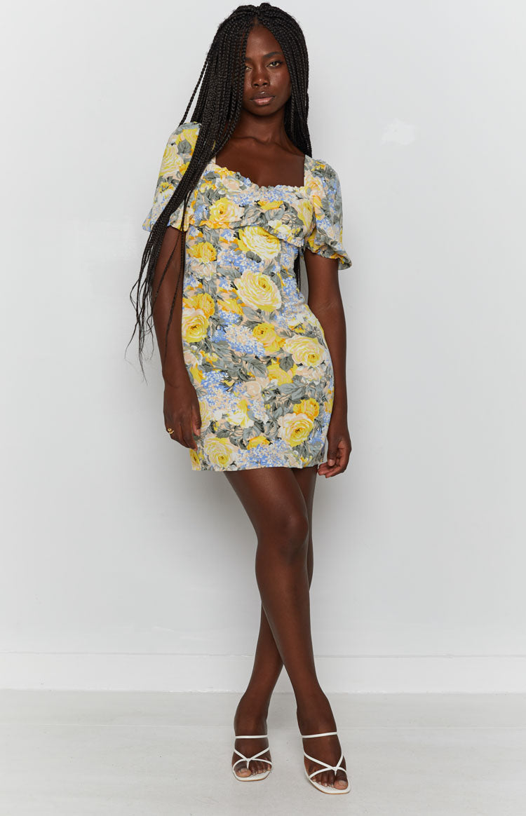 Yellow, blue, and green floral mini dress with a ruffled square neckline and short puffed sleeves
